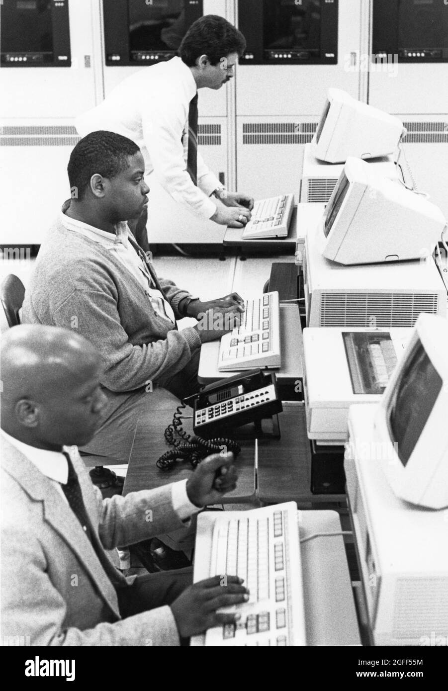 Austin Texas USA, 1990: Supervisor works on computer terminal in front of mainframe computers at  United States Census regional data processing center. ©Bob Daemmrich Stock Photo