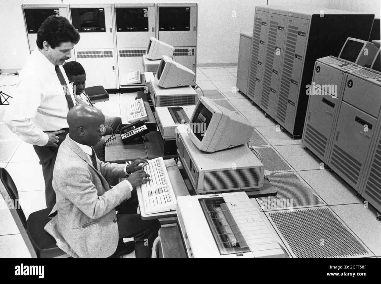 Austin Texas USA, 1990: Supervisor works on computer terminal in front of mainframe computers at  United States Census regional data processing center. ©Bob Daemmrich Stock Photo