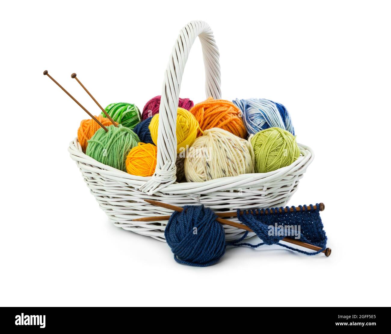Balls of woolen threads for knitting in wicker basket isolated on white background. Stock Photo
