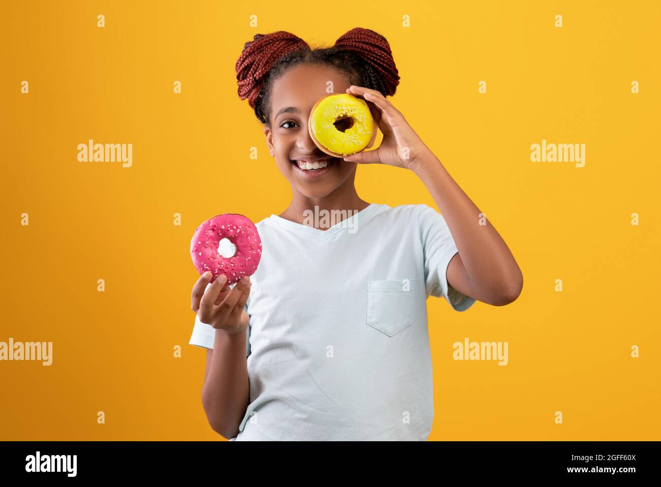 Cute afro american girl holding donut over eye Stock Photo