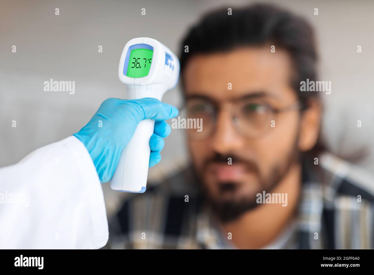 Nurse hand with thermometer against arab guy forehead Stock Photo Alamy