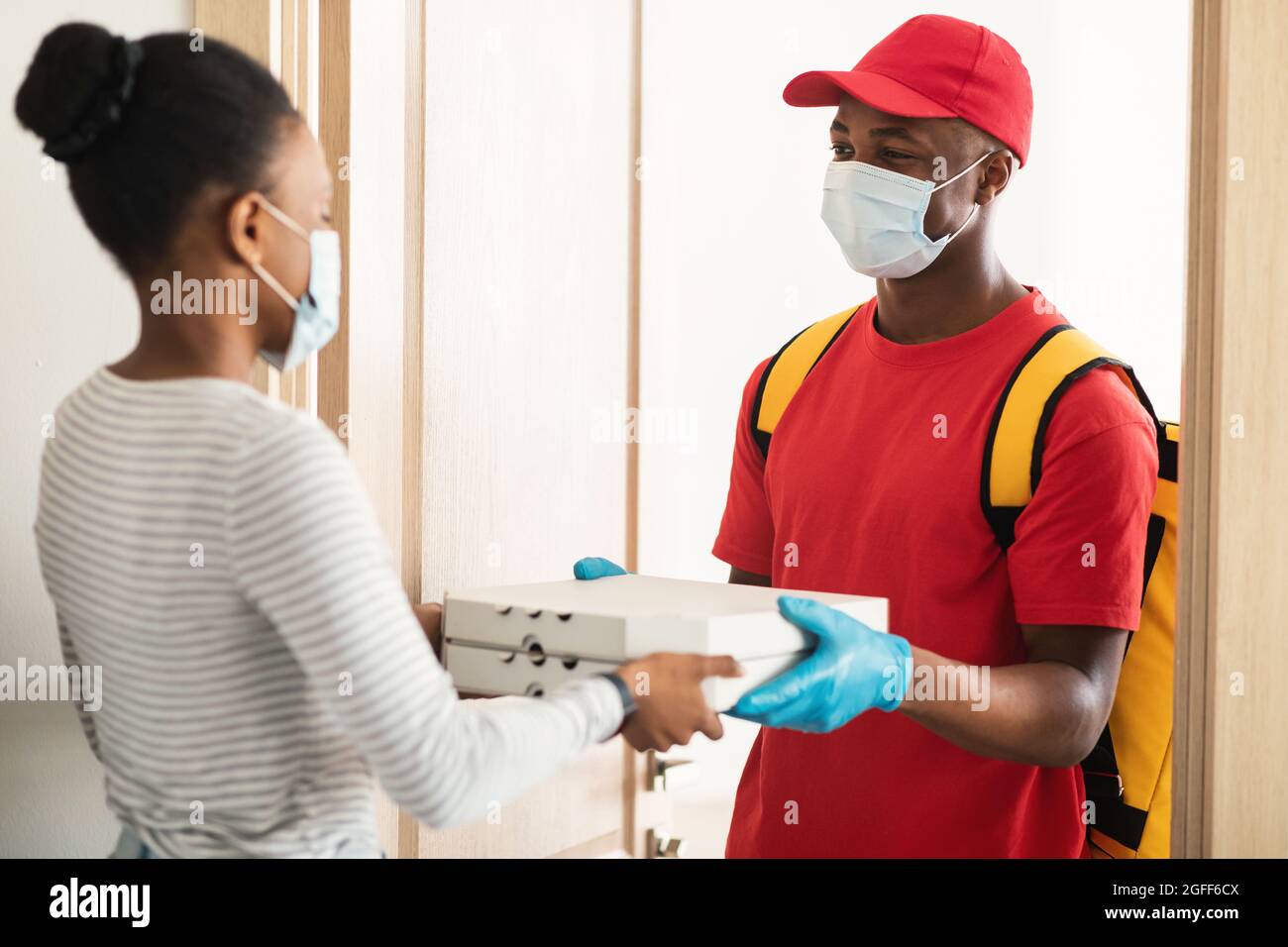 Black Woman Receiving Order Taking Pizza Boxes From Deliveryman Indoor Stock Photo