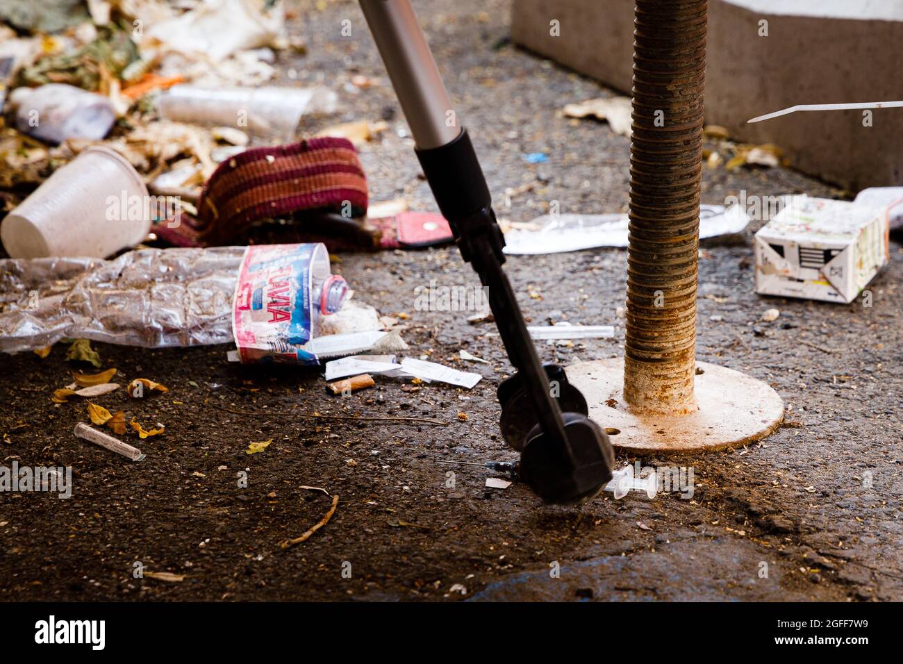 Heroin syringe gathering from the ground, Italy Stock Photo