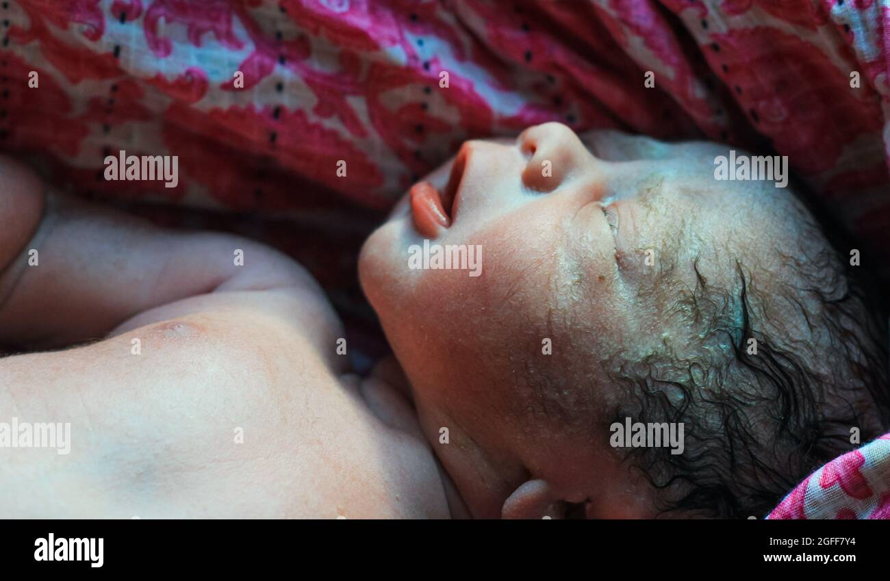 Beautiful baby boy a few seconds after the birth. Baby after birth. Stock Photo