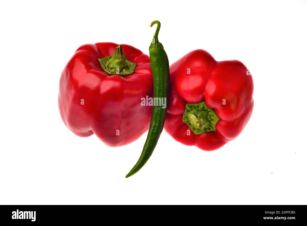 two red bell peppers and one green hot pepper on a white background ...