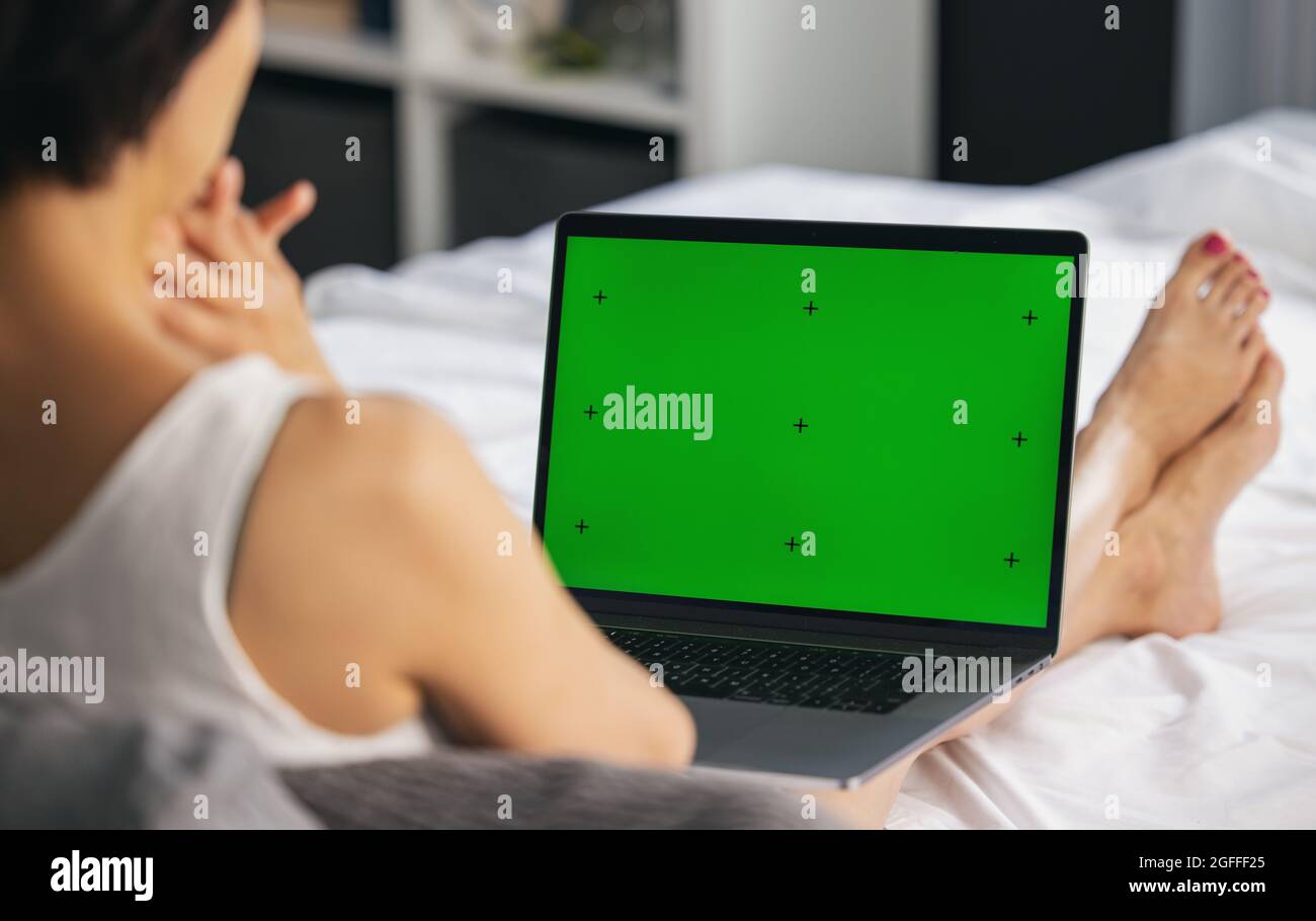 Woman with laptop on bed Stock Photo