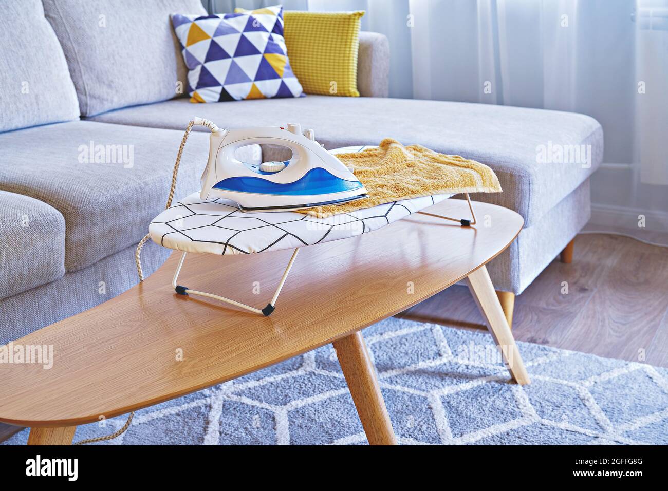Iron for ironing on small tabletop ironing board in cozy and living