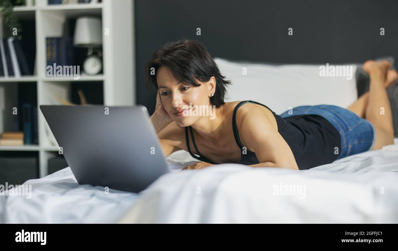 Woman lying with laptop on bed Stock Photo - Alamy