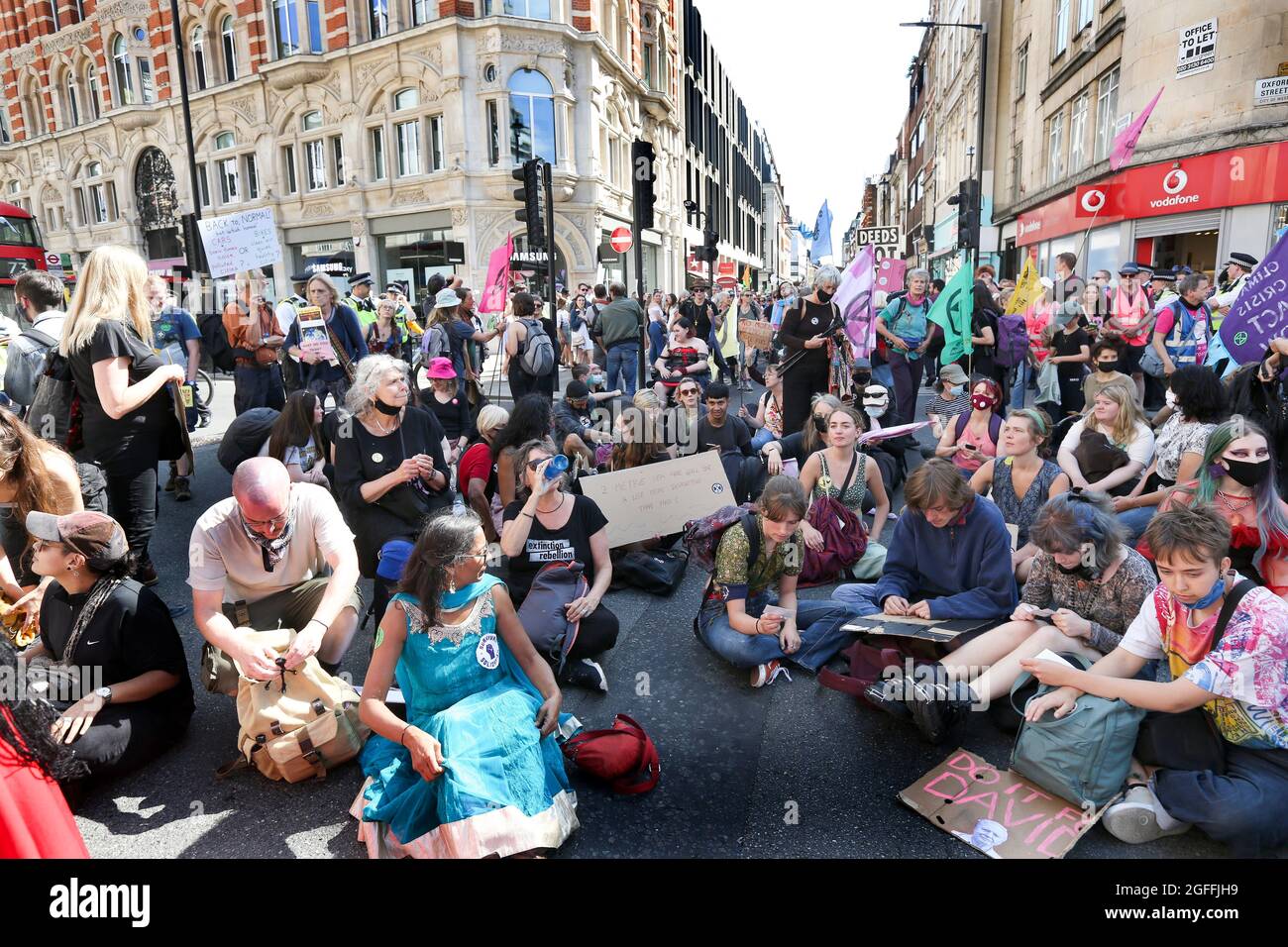 London, UK. 25th Aug, 2021. Protesters sitting on the ground at Oxford Circus, during the Impossible Rebellion - Day 3. Led by Female, Intersex, Non-binary and Trans (FINT) people from Extinction Rebellion, rebels demand that government change policies to address the ecological and climate emergency and immediately stop all new fossil fuel investments. Credit: SOPA Images Limited/Alamy Live News Stock Photo
