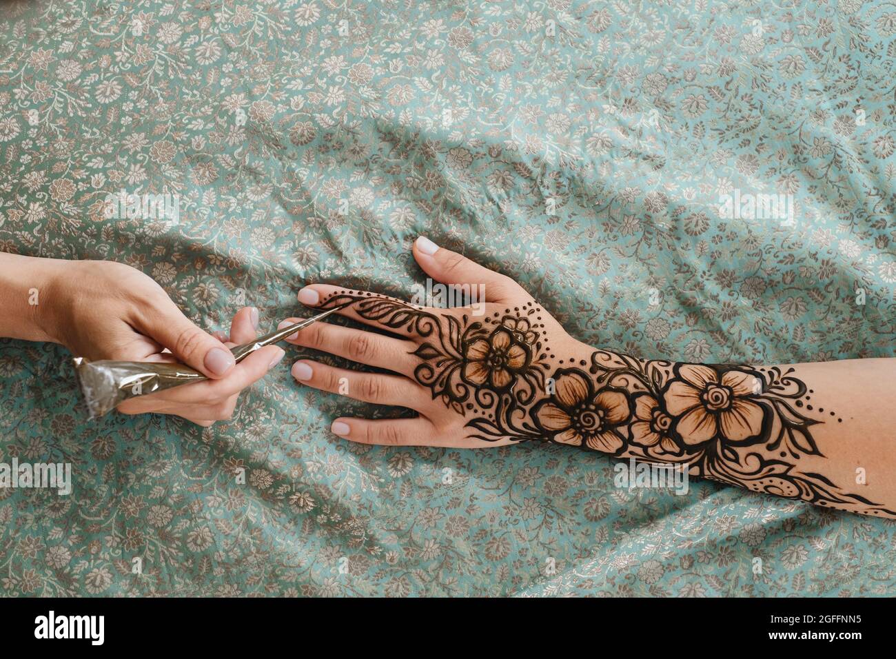 Top view art henna tattoo on woman hands. master artist drawing Arabic  mehndi for bride before wedding. Close-up, overhead view. Floral design.  Cone Stock Photo - Alamy