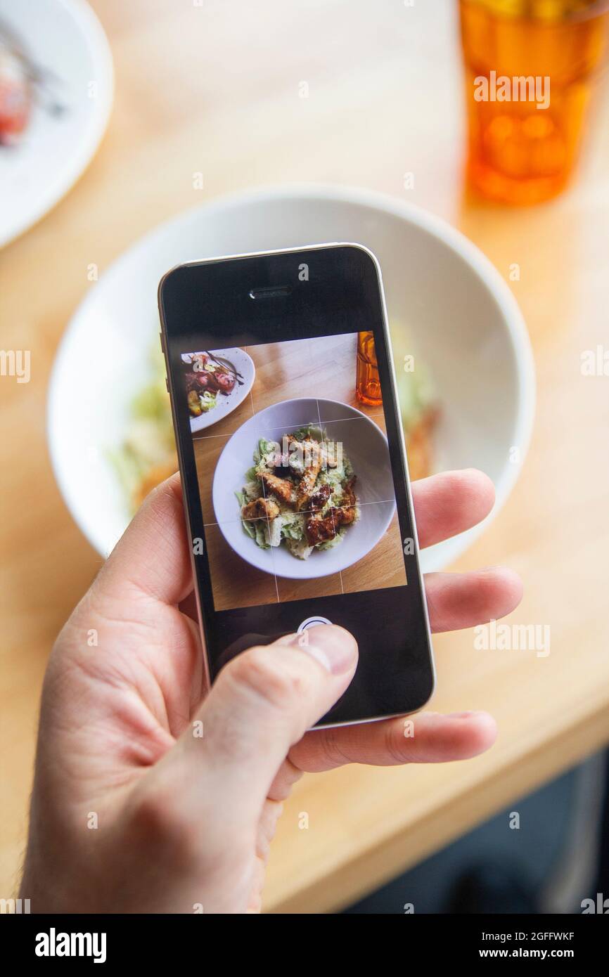 A man photographs a delicious salad on his phone in a restaurant Stock Photo