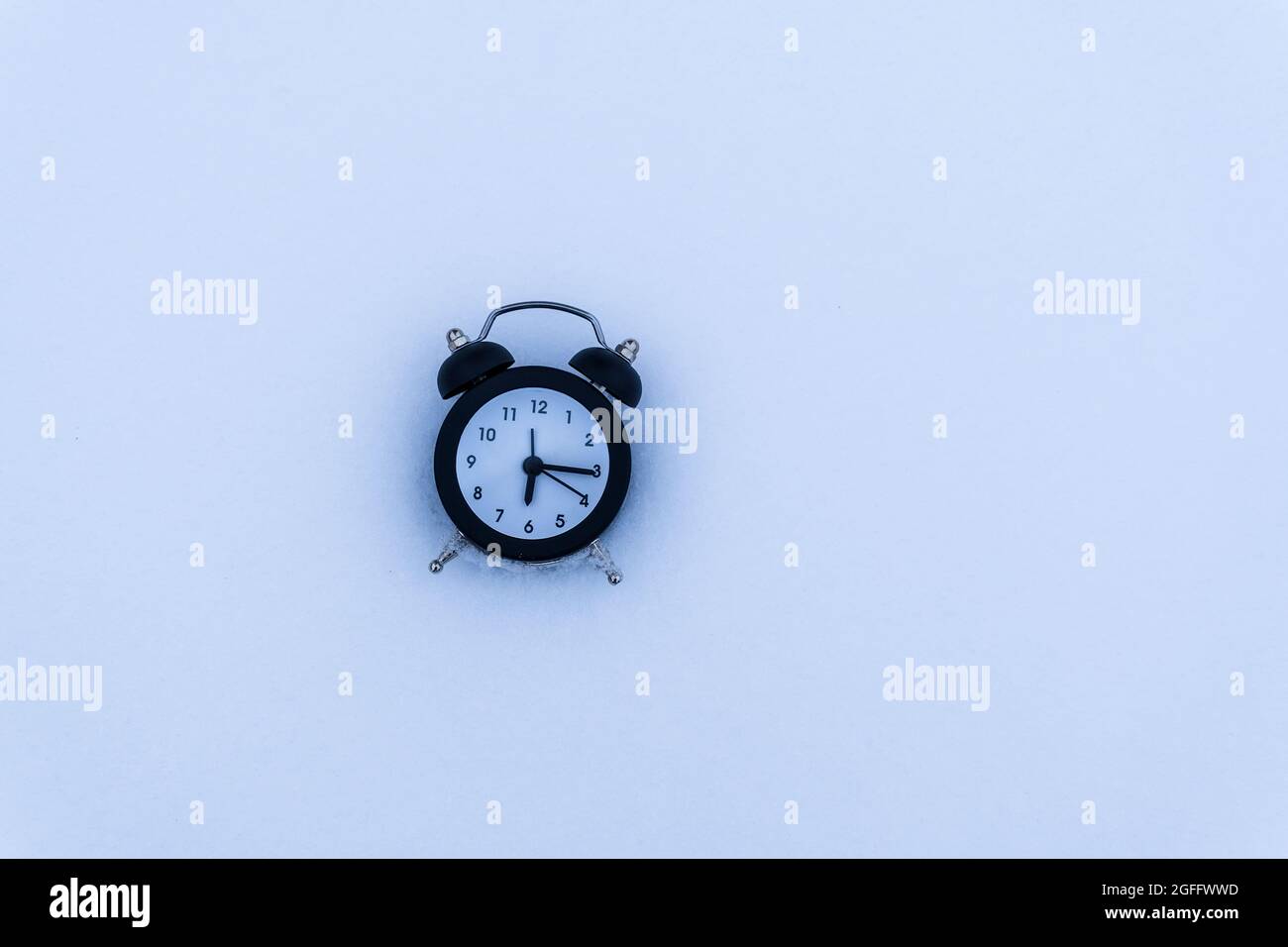 alarm clock in snowy weather on a winter background. Return to winter ...