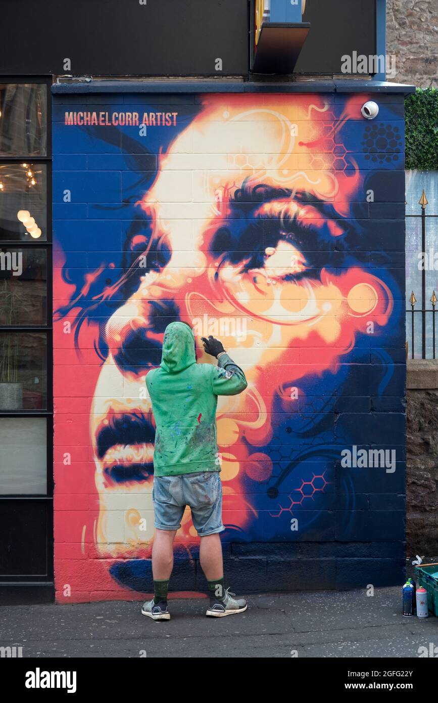 Artist working on a commissioned piece of street art in the Cowgate, Edinburgh, Scotland, UK. Stock Photo