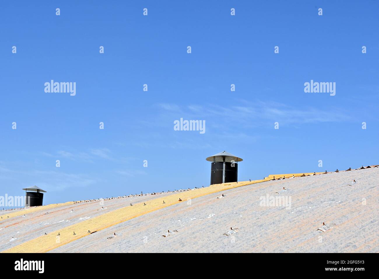 Ventilation system on sheet metal roof of industrial factory shed. Blue Sky. Stock Photo