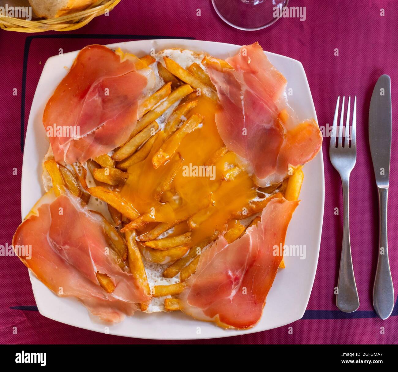 Fried eggs with fried potatoes and sliced cured ham Stock Photo