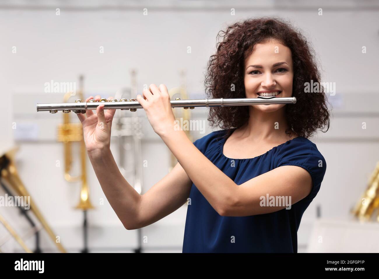 Beautiful girl playing flute in music shop Stock Photo - Alamy