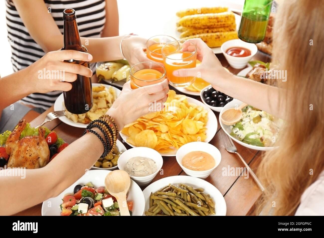 Friends cheering with orange juice and beer in restaurant Stock Photo
