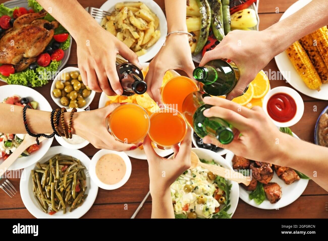 Friends cheering with orange juice and beer in restaurant Stock Photo