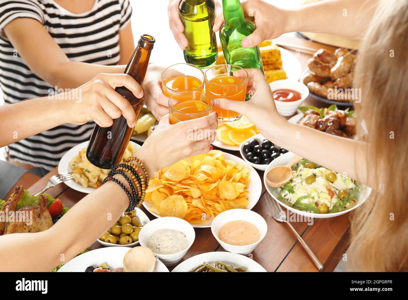 Friends cheering with orange juice and beer in restaurant Stock Photo
