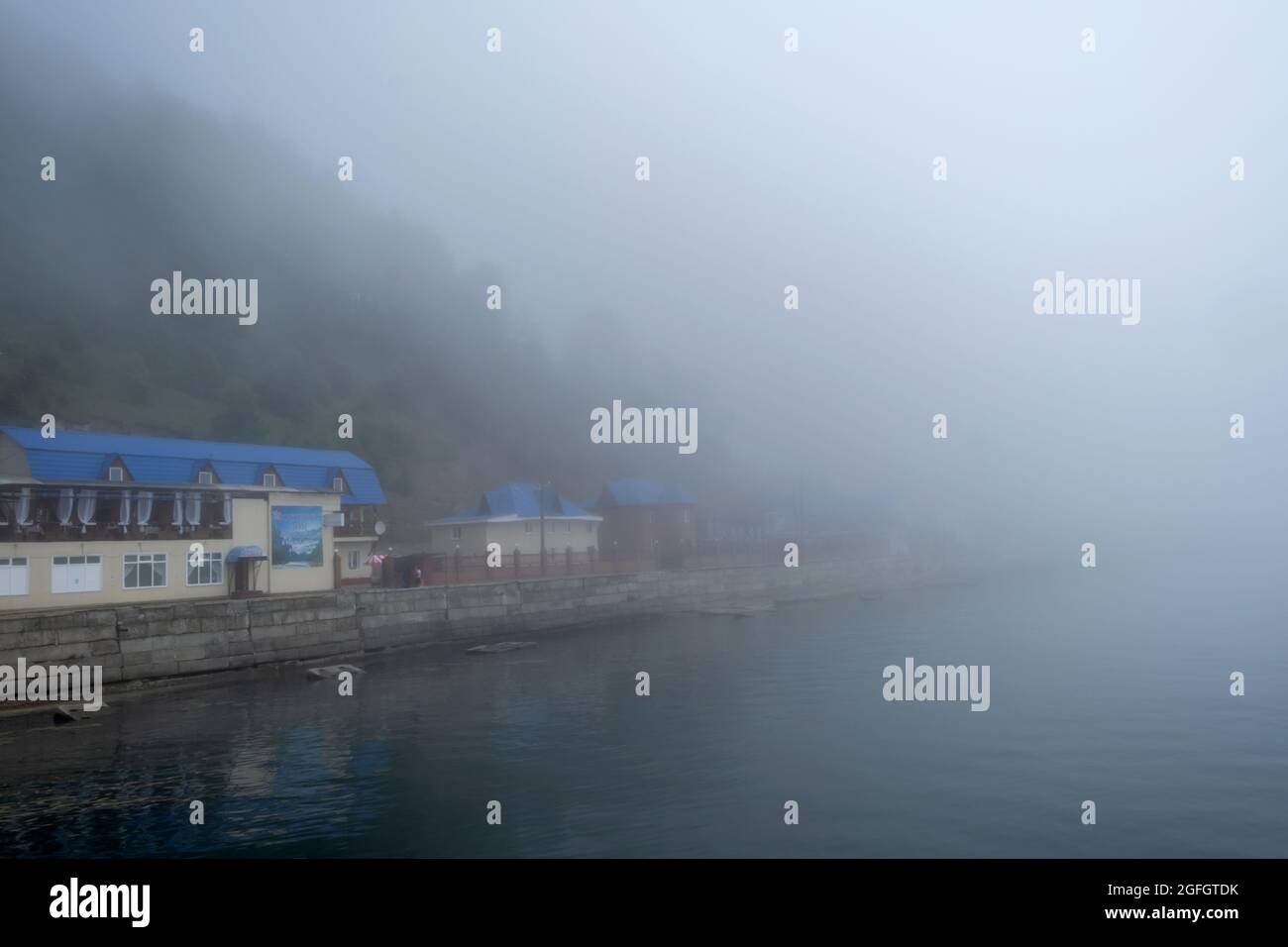 Peaceful scene of lake Baikal with pier on water at morning with fog Stock Photo