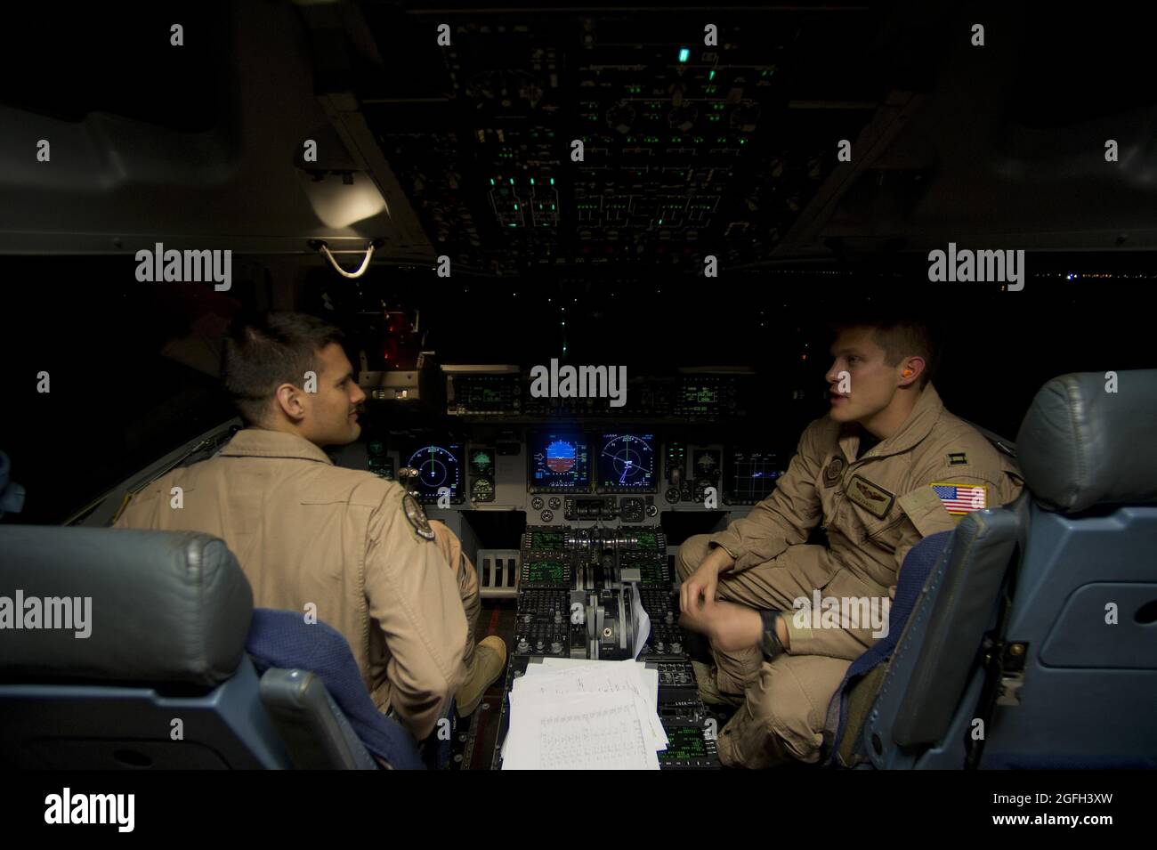 Capt. Travis Kuenzi and 1st Lt. Alexander Hanna, 816th  Expeditionary Airlift Squadron, chat as they prepare to conduct engine start up procedures on a C-17 Globemaster III prior to an air delivery mission. The C-17 aircrew air delivered cargo which consisted of fuel and other various supplies to a remote forward operating base in Afghanistan. Kuenzi and Hanna are deployed from the 7th Airlift Squadron, McChord Air Force Base, Wash. Stock Photo