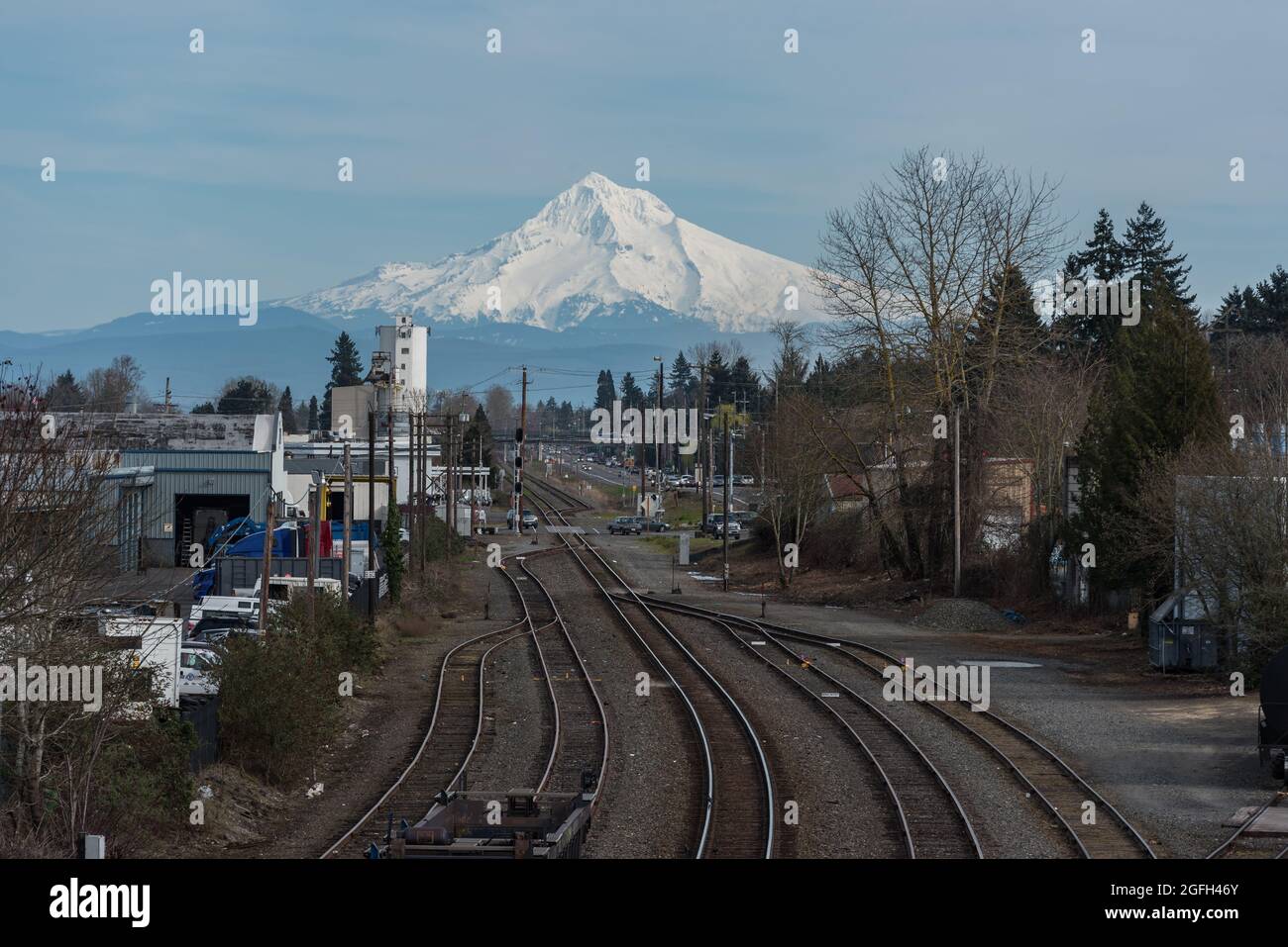 Nature and urban together with views of snowy Mt Hood mountain peak over industrial train tracks in Portland, Oregon, Pacific Northwest United States Stock Photo
