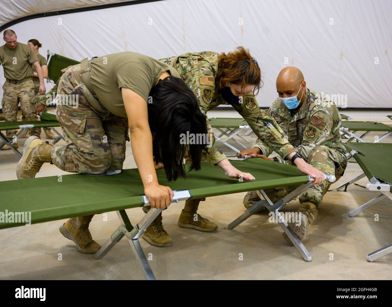 U.S. Air Force personnel construct cots for qualified evacuees during a layover stop of a C17