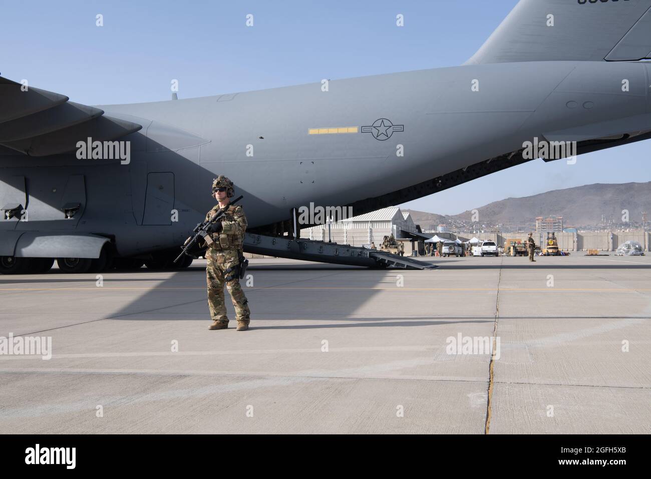 A U.S. Air Force security forces raven, assigned to the 816th Expeditionary Airlift Squadron, maintain a security cordon around a U.S. Air Force C-17 Globemaster III aircraft in support of the Afghanistan evacuation at Hamid Karzai International Airport (HKIA), Afghanistan, Aug. 24, 2021. (U.S. Air Force photo by Master Sgt. Donald R. Allen) Stock Photo