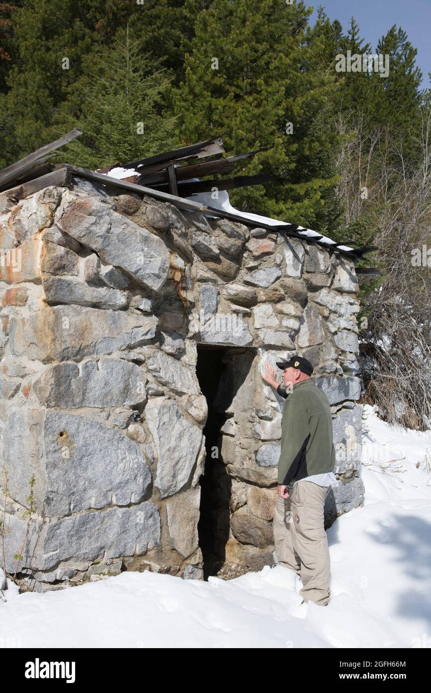 Visitor gives scale to the masonry vault, all that remains of the Hyde & Freychlag Bank, Granite Ghost Town State Park, MT. (MR) Stock Photo
