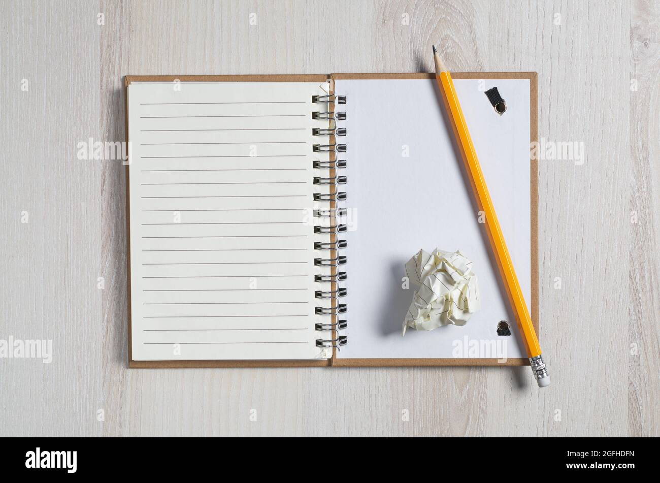 Open notepad, crumpled paper and pencil on light wooden background, top ...