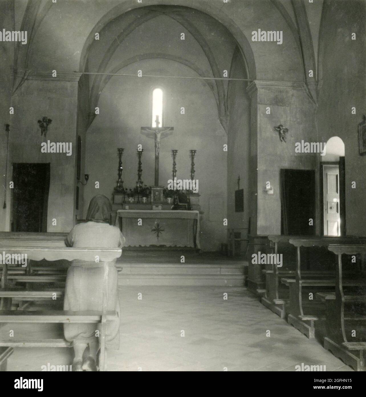 Woman praying in a church down on her knees, Italy 1930s Stock Photo