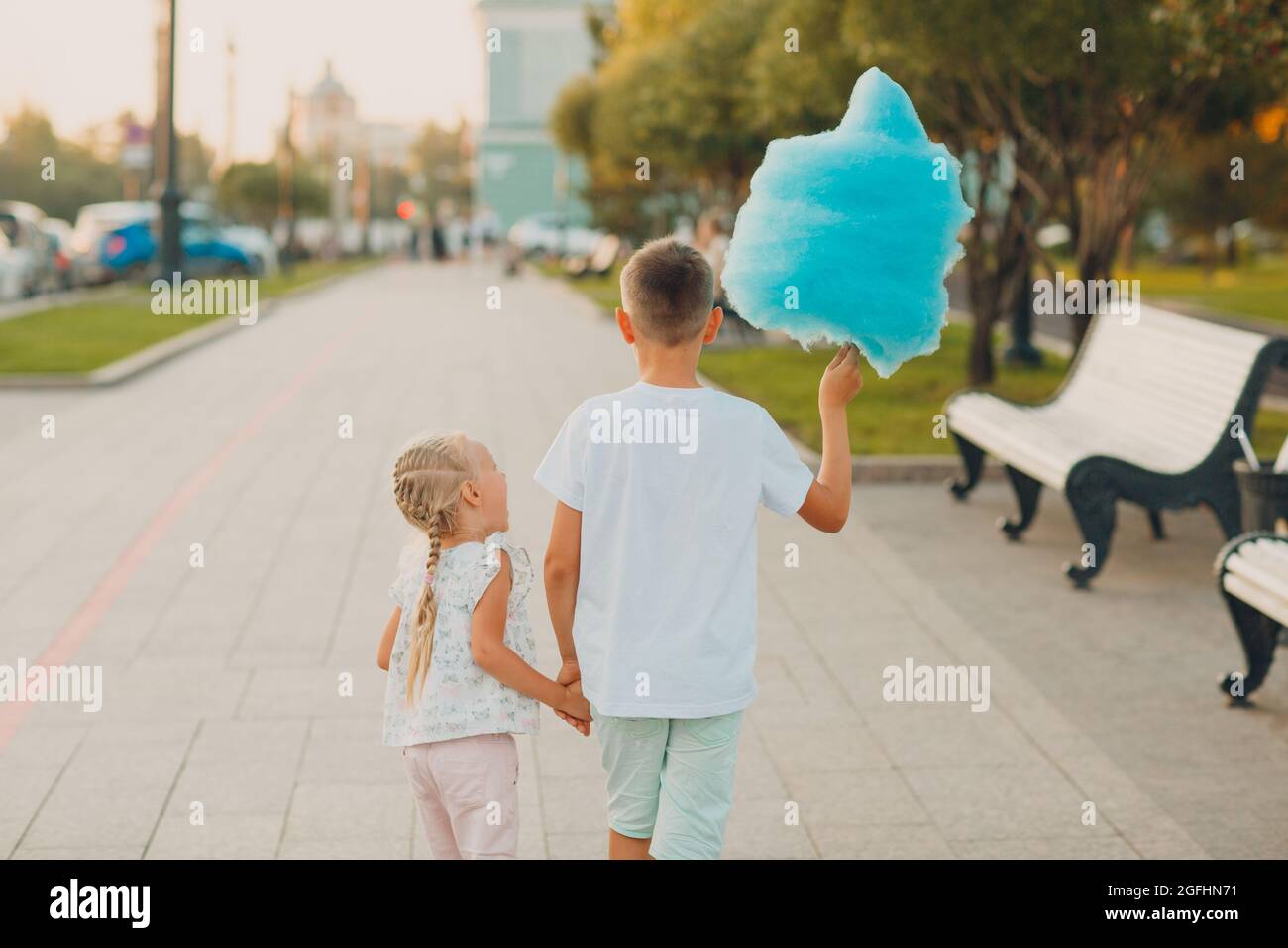 Happy children boy and girl eating blue cotton candy outdoors. Stock Photo