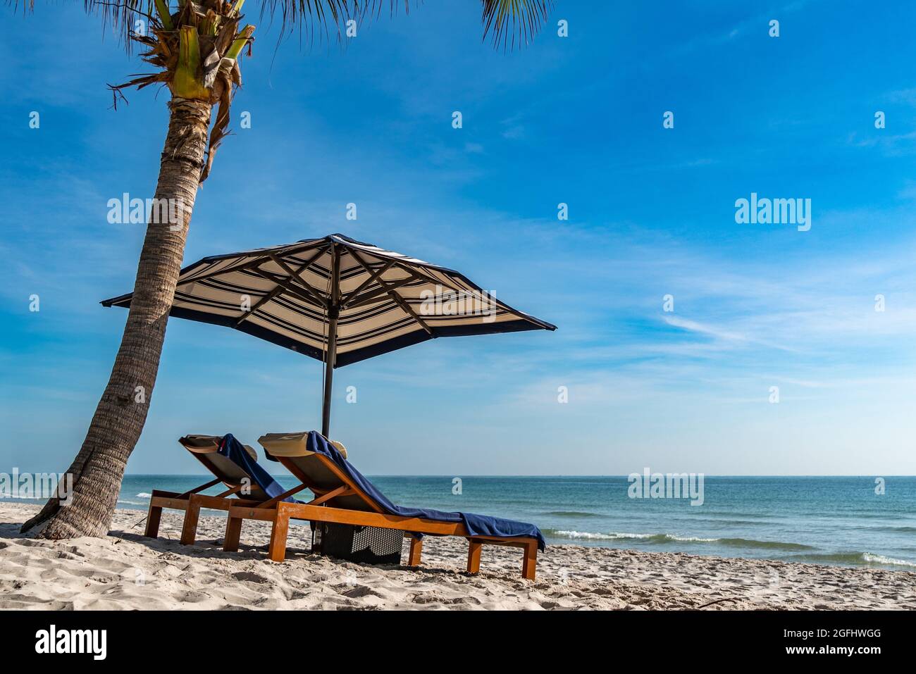 Couple Beach chair umbrella under coconut tree in the morning. Stock Photo