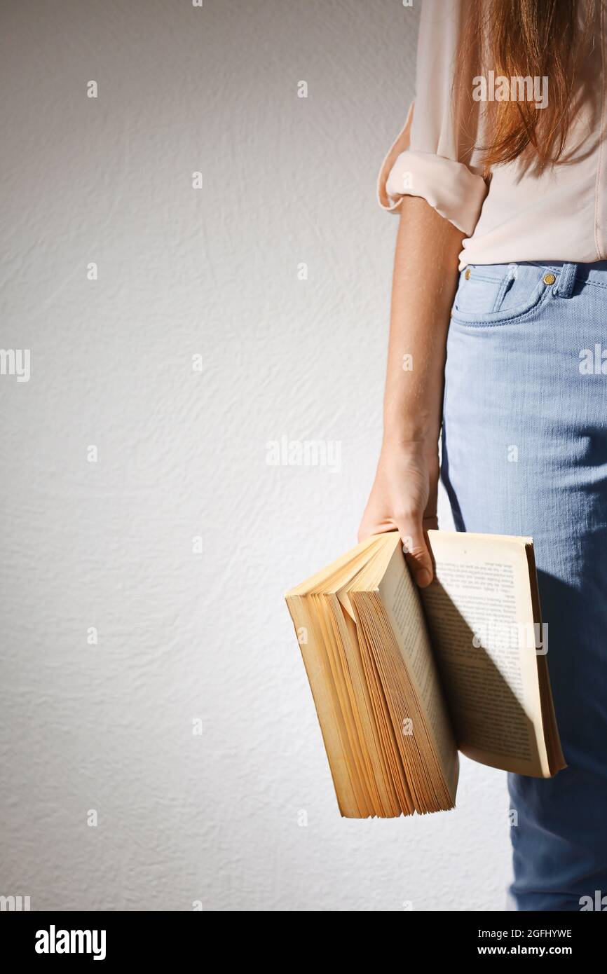 Female hand holding book on light background Stock Photo - Alamy