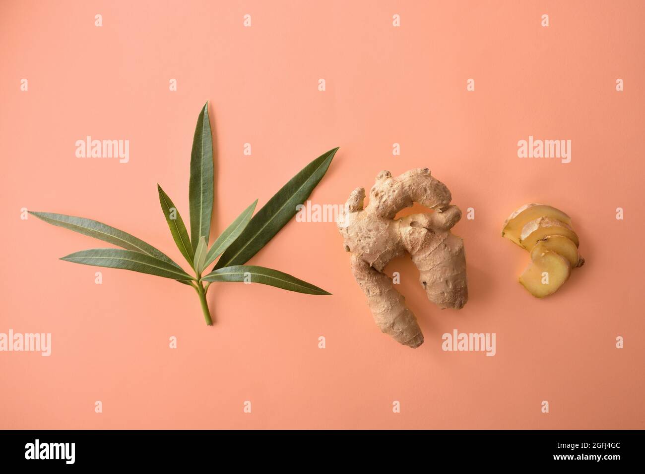 Composition with ginger root leaves and sliced portions on orange background. Top view Stock Photo