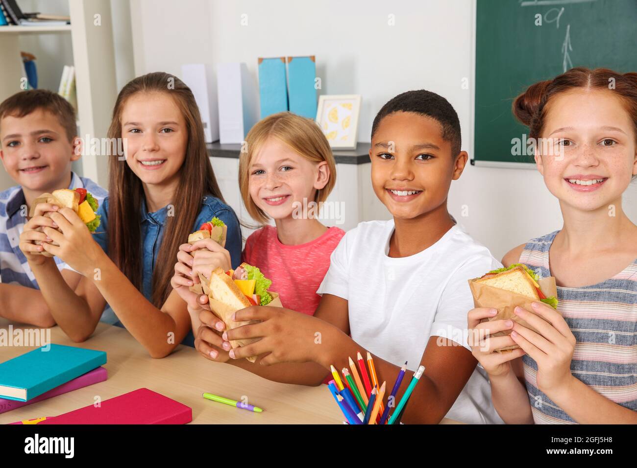 Schoolchildren having lunch in classroom Stock Photo - Alamy