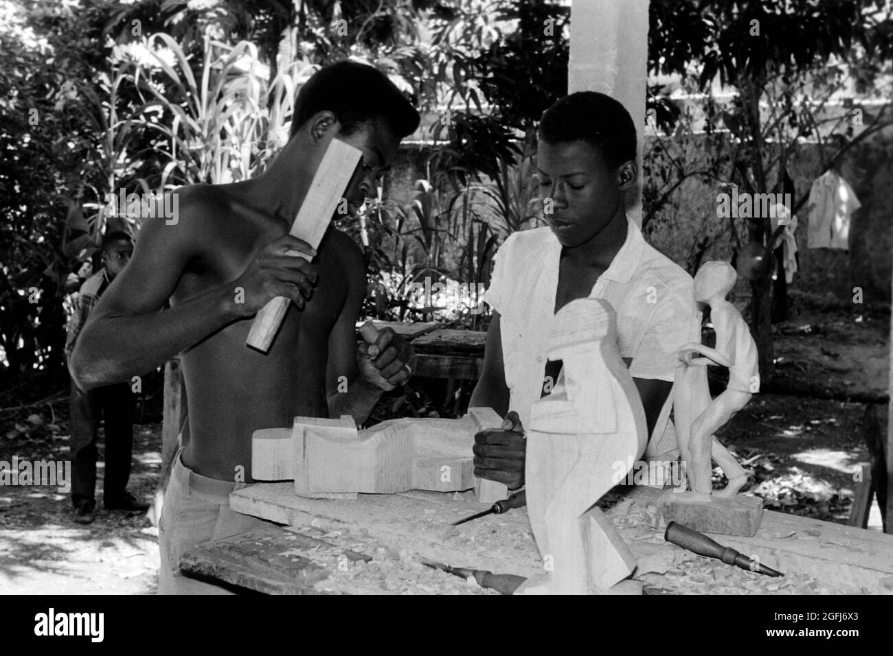 Kunsthandwerker schnitzen typische Skulpturen in Port-au-Prince, Haiti, 1966. Artisans carving typical wooden sculptures in Port-au-Prince, Haiti, 1966. Stock Photo
