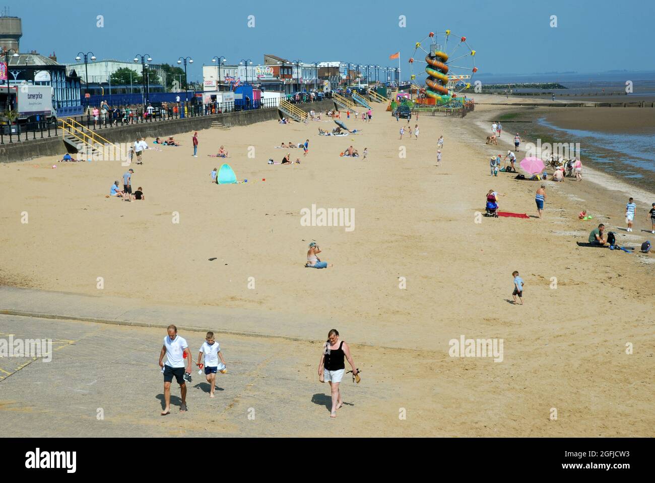 People enjoying the summer sunshine on a sandy beach in the picturesque seaside town of Cleethorpes, Lincolnshire. UK. Stock Photo