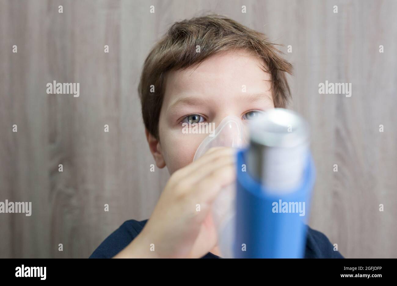 Child boy using medical spray for breath. Inhaler, spacer and mask. Front view Stock Photo