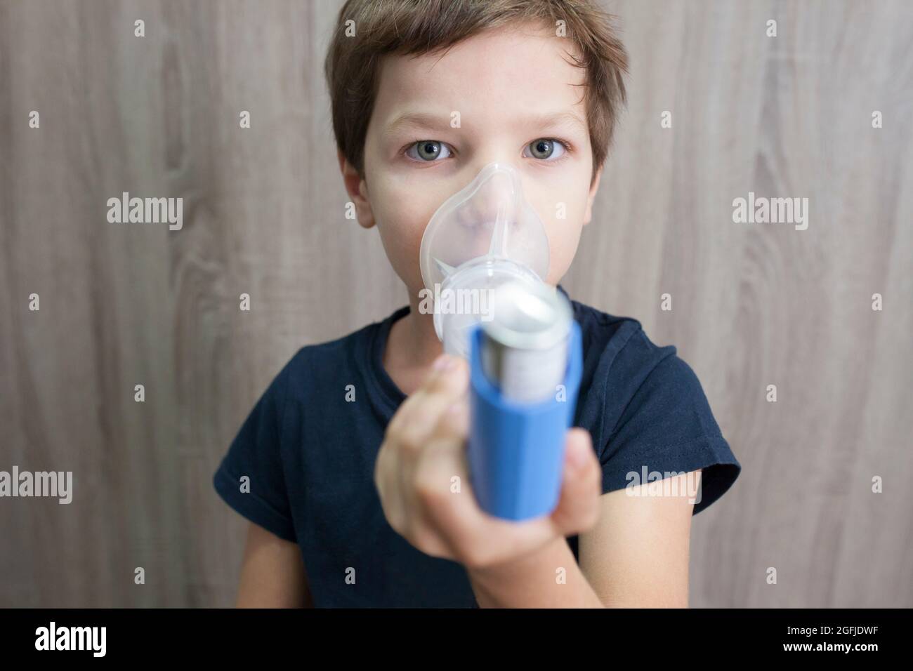 Child boy using medical spray for breath. Inhaler, spacer and mask. Front view Stock Photo