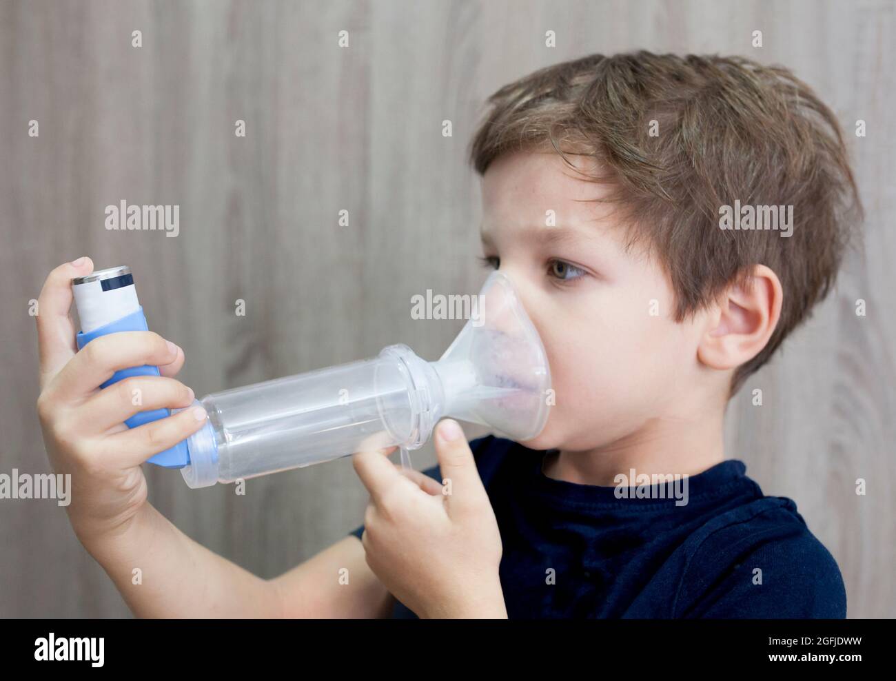 Child boy using medical spray for breath. Inhaler, spacer and mask. Side  view Stock Photo - Alamy