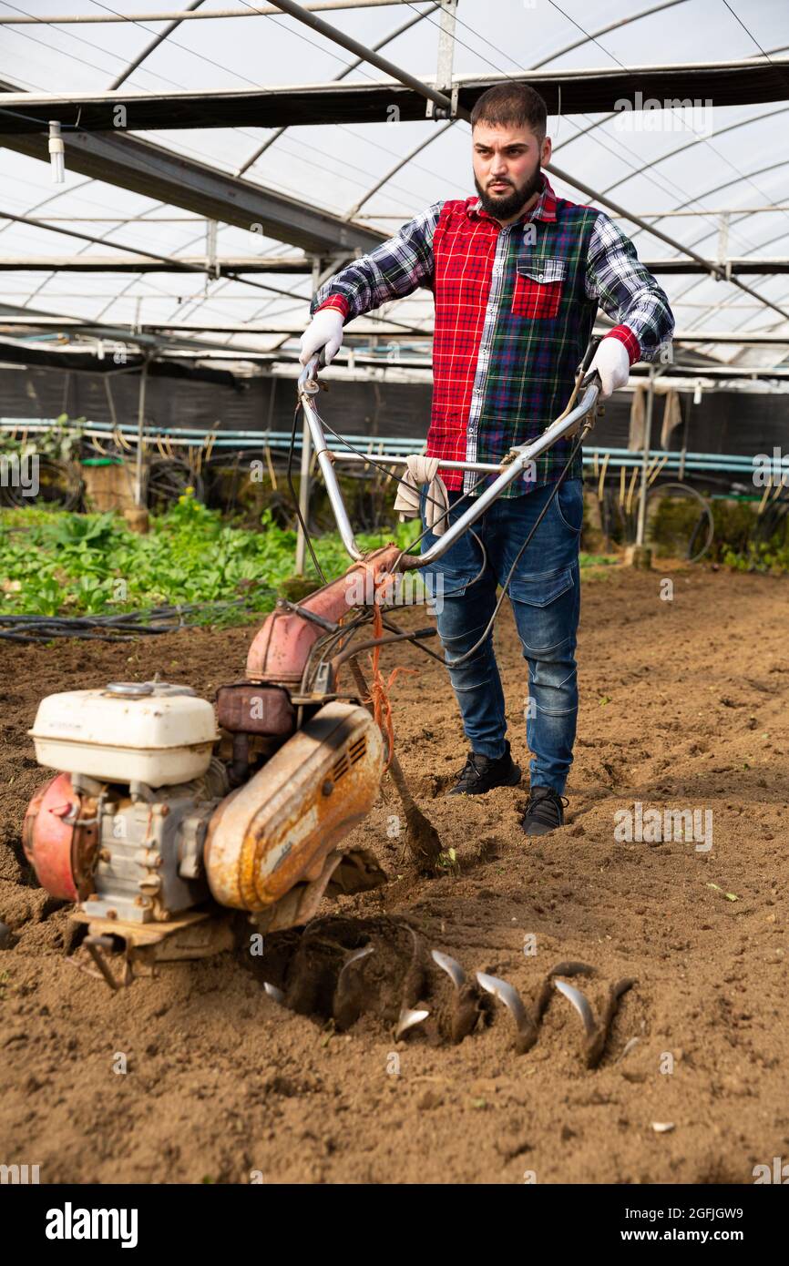 Gardener using motorized cultivator in greenhouse Stock Photo - Alamy