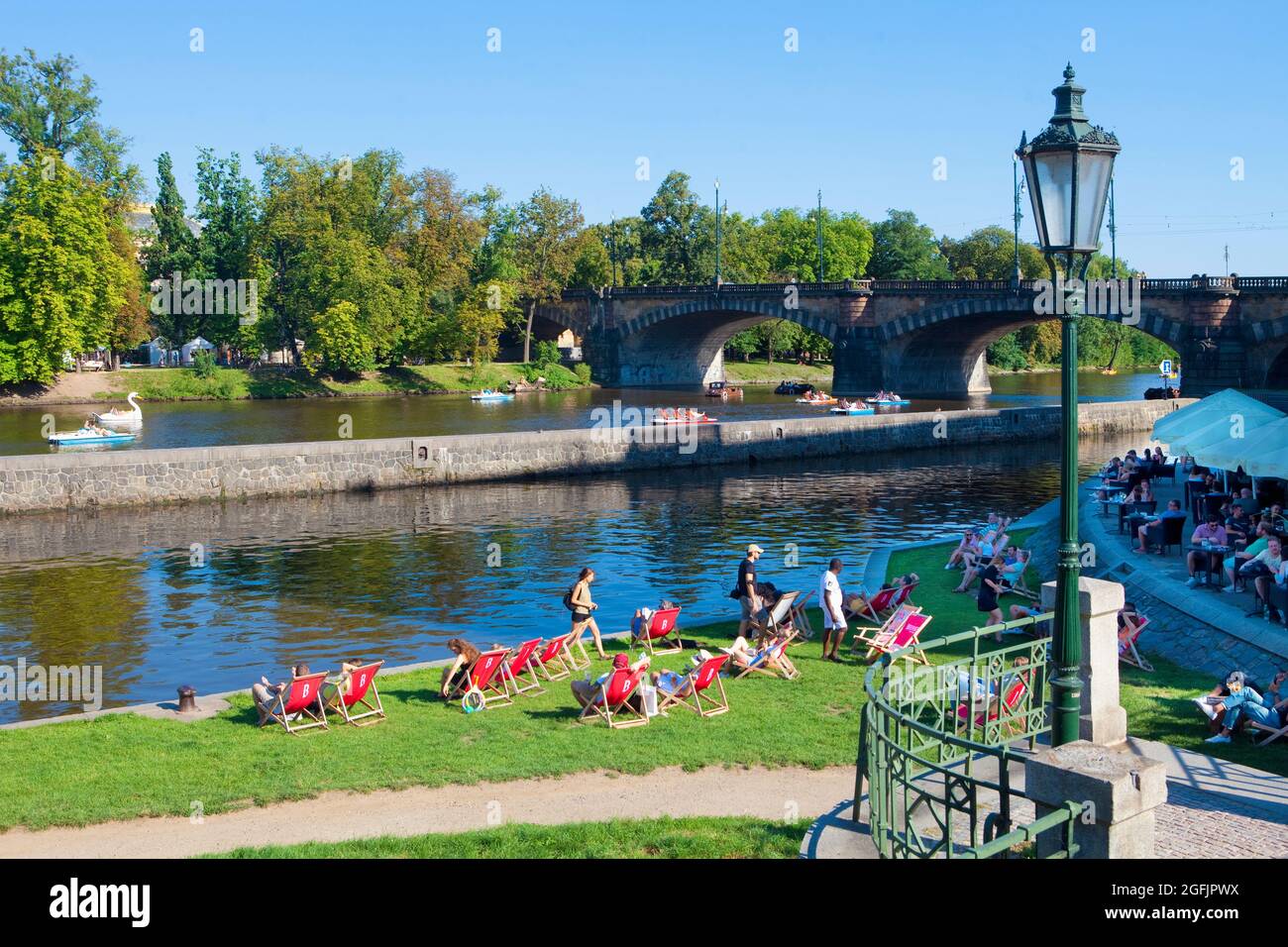 Prague - people at restaurant at Lesser Quarter watching pedal boats. Stock Photo