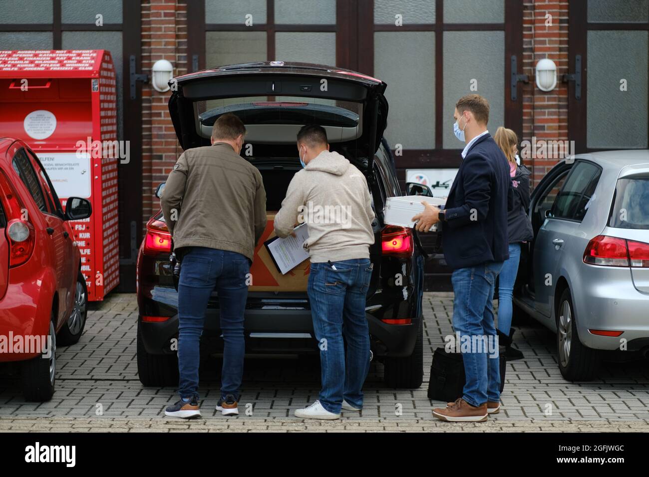 Varel, Germany. 26th Aug, 2021. Civilian police officers carry boxes and crates into a civilian police vehicle in front of the DRK building. In the morning hours, officers searched several buildings of the German Red Cross (DRK) in Friesland. The Soko 'Vakzin' found further irregularities during its investigations. (to dpa 'Searches during investigations into saline injections') Credit: Markus Hibbeler/dpa/Alamy Live News Stock Photo