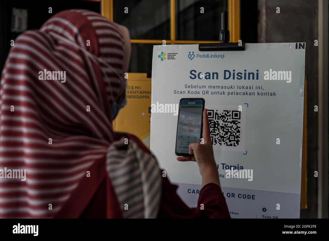 Makassar, South Sulawesi, Indonesia. 26th Aug, 2021. A woman enters the  mall by scanning a barcode that has been vaccinated against Covid-19, which  is in front of the entrance to the Ratu