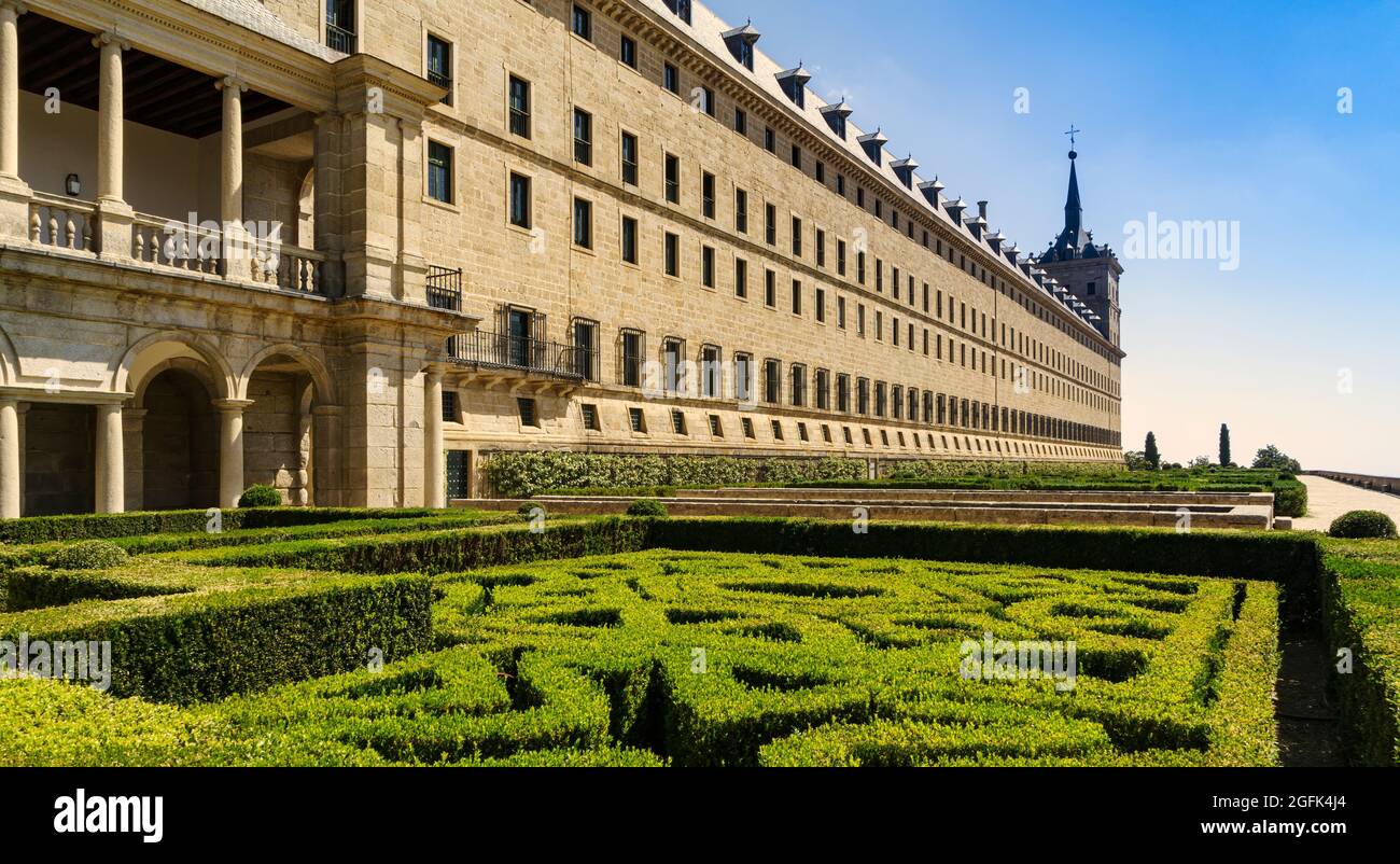 View of the San Lorenzo de el Escorial in Madrid, with gardens in the foreground and blue sky with light white clouds. Stock Photo