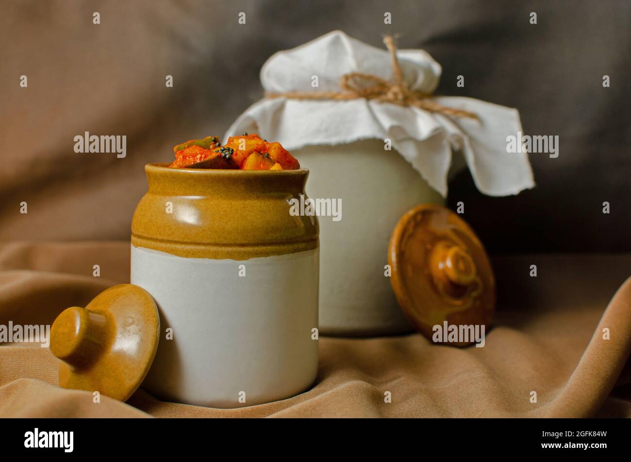 Homemade raw mango pickle in a traditional ceramic jar on Brown background Stock Photo
