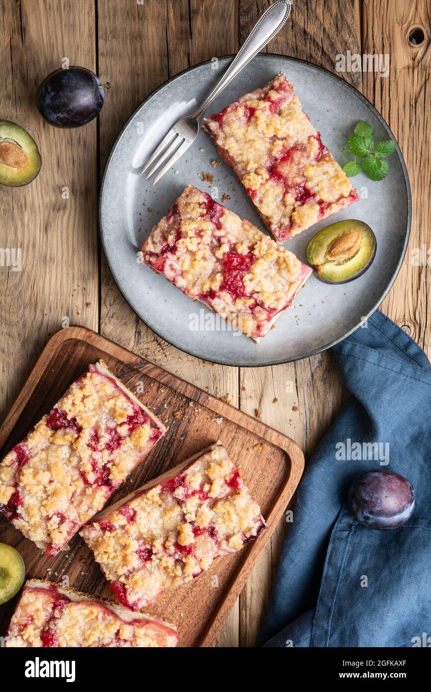 Juicy plum pie slices with crunchy streusel topping on rustic wooden background Stock Photo