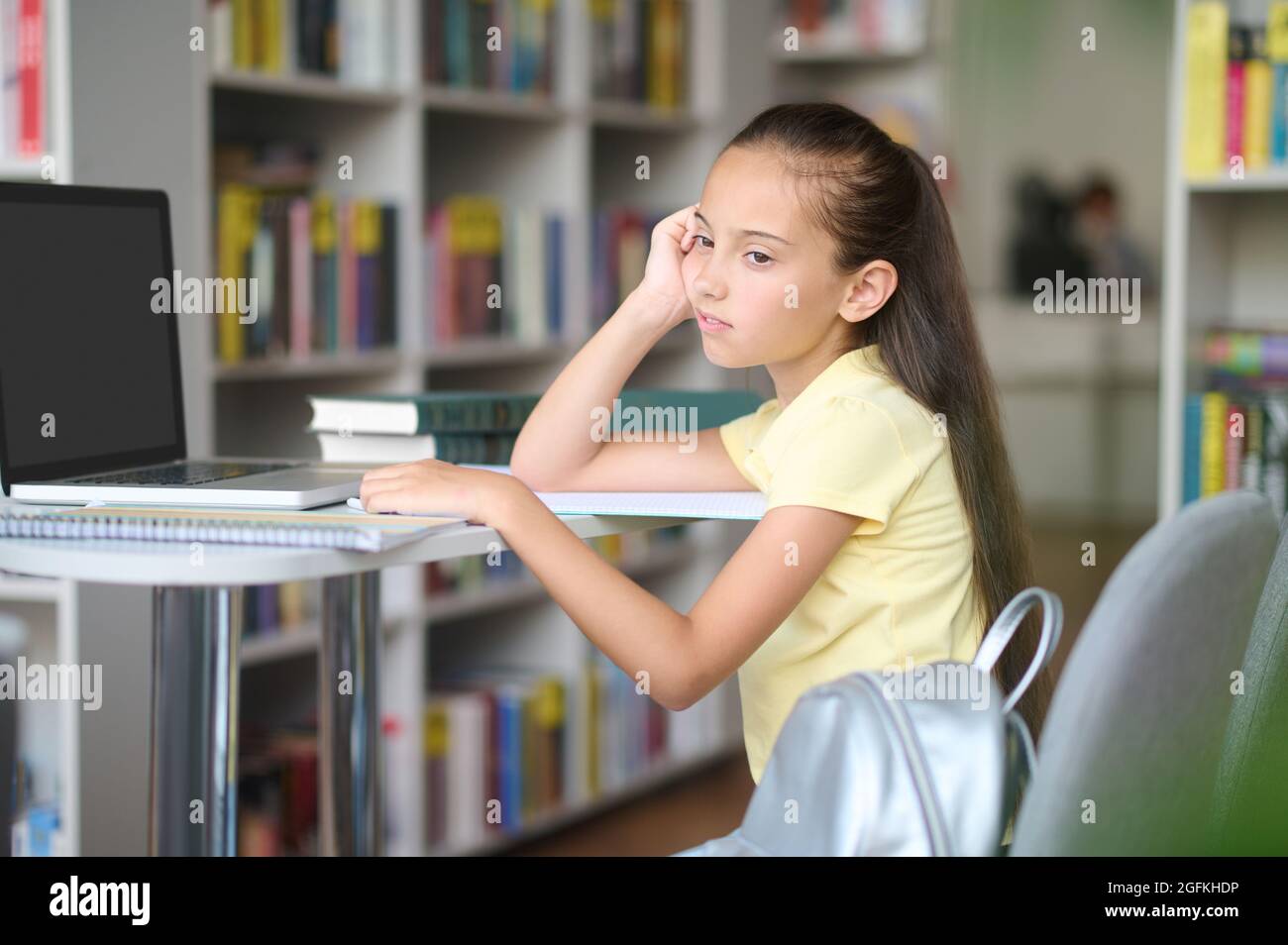 Pupil with a faraway look on her face at the desk Stock Photo
