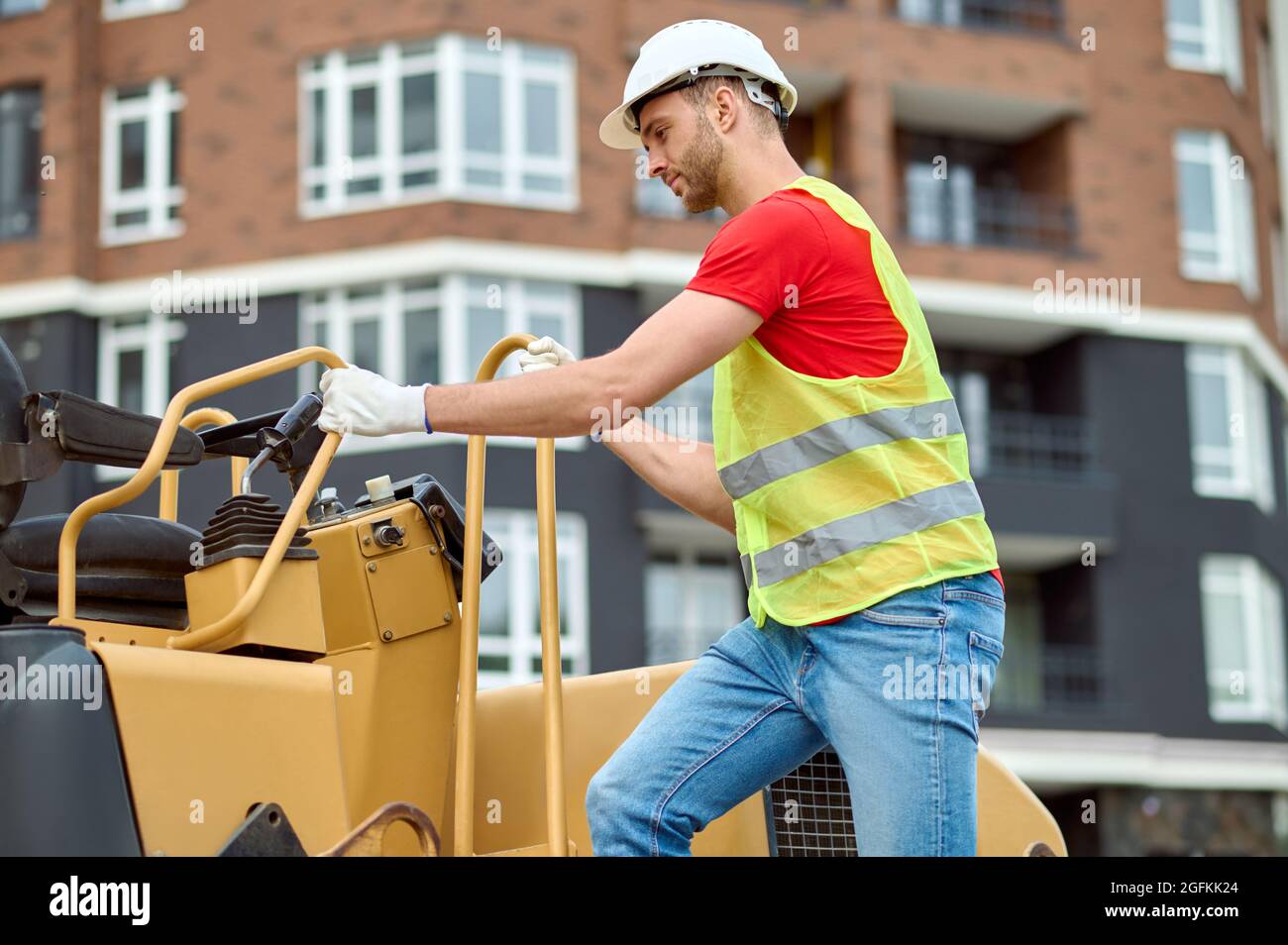 Concentrated skilled worker in a safety helmet using construction equipment Stock Photo